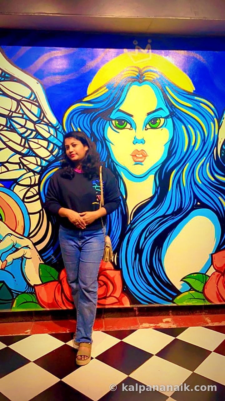 Kalpana in front of a colourful mural