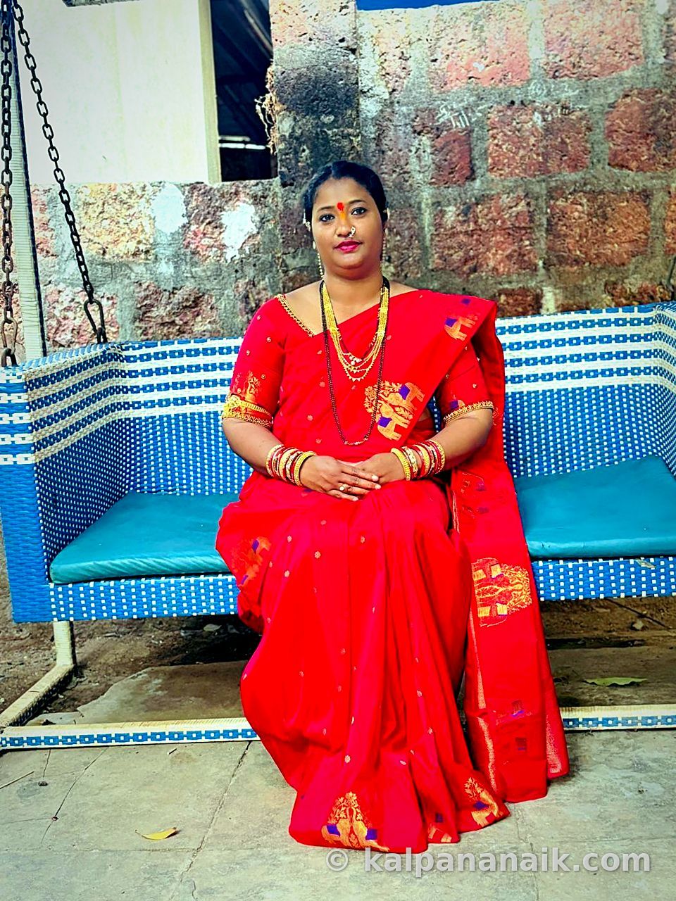 Kalpana in red silk seated on a swing