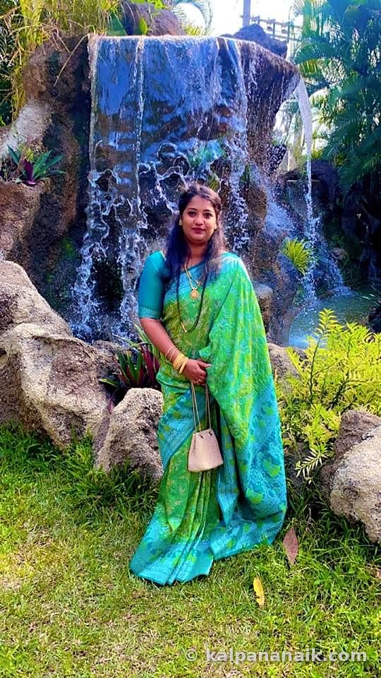 Kalpana in a green silk saree by a waterfall