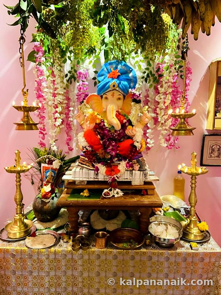 Ganpati altar with brass lamps and flowers